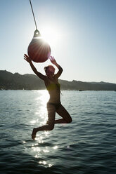 Junge Frau, die an einem Bootsfender schwingt, Sausalito, Kalifornien, USA - CUF33260