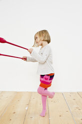 Studio shot of young girl juggling on one leg - CUF33285