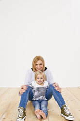 Studio-Porträt von Mutter und Tochter auf dem Boden sitzend - CUF33330