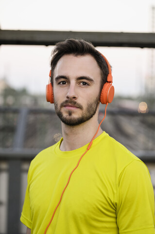 Porträt eines jungen männlichen Läufers mit Kopfhörern, lizenzfreies Stockfoto