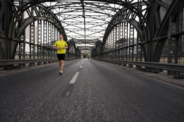 Junger männlicher Sportler läuft auf einer Brücke - CUF33369