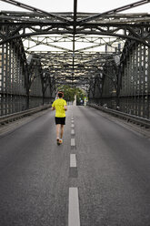 Junger männlicher Sportler läuft über eine Brücke - CUF33370