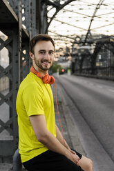 Porträt eines jungen männlichen Läufers, der auf einer Brücke eine Pause macht - CUF33372