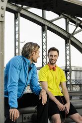 Two male runners chatting on bridge - CUF33373