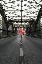 Young female runner crossing bridge - CUF33374