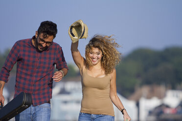 Young couple laughing, woman holding hat - CUF33424