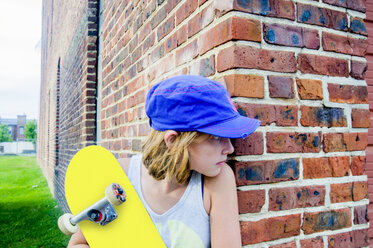 Tomboy Skateboarder Mädchen späht um Ziegelmauer Ecke - ISF14144