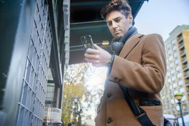 Young man in street, using smartphone - ISF14147