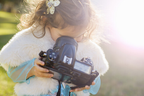 Weibliches Kleinkind im Garten, das in die Linse der Kamera blickt, lizenzfreies Stockfoto