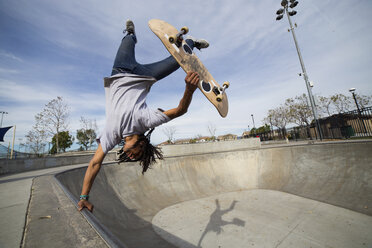 Junger Mann macht Skateboardtrick kopfüber auf dem Rand eines Skateboardparks - ISF14158