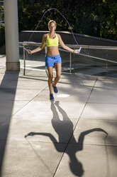 Junge Sportlerin beim Springen im städtischen Sonnenlicht - CUF33489