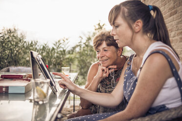 Mutter und Tochter im mittleren Erwachsenenalter betrachten ein digitales Tablet - CUF33493