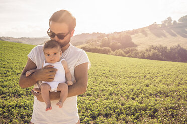 Portrait of proud father holding up baby daughter - CUF33495