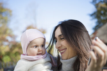 Mother showing cellular phone to baby - CUF33543