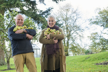 Glückliches Seniorenpaar mit einem Arm voller Äpfel - CUF33566
