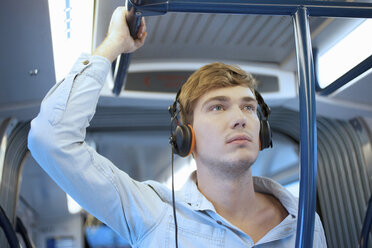 Junger Mann im Zugwaggon mit Kopfhörern - CUF33612