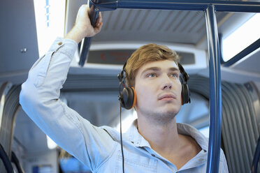 Young man in train carriage listening to headphones - CUF33612