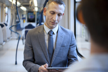 Businessman using digital tablet on train - CUF33613