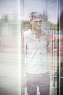 Unglücklicher junger Mann hinter reflektierendem Fenster - CUF33618