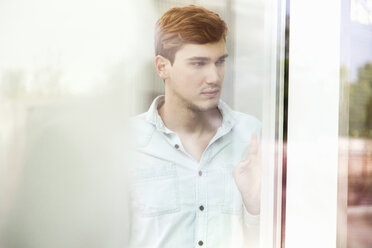 Unhappy young man looking out of window - CUF33619