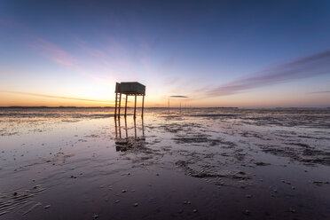 Vereinigtes Königreich, England, Northumberland, Pfosten zur Markierung des Pilgerwegs nach Lindisfarne mit Notunterkunft, Sonnenaufgang - SMAF01043