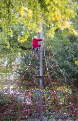 Kleines Mädchen klettert auf Klettergerüst im Herbst - JFEF00883
