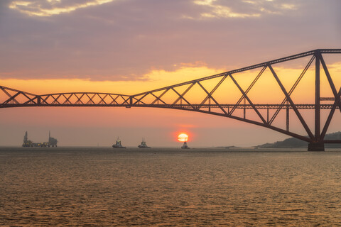 Vereinigtes Königreich, Schottland, Firth of Forth, Forth Rail Bridge mit Schleppern darunter und Hound Point Oil Loading Marine Terminal bei Sonnenuntergang, lizenzfreies Stockfoto