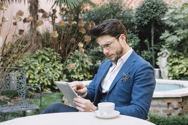 Eleganter Geschäftsmann mit Tablet in einem Gartencafé - ALBF00539
