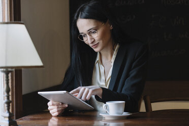 Smiling young businesswoman using tablet in a cafe - ALBF00557