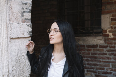 Young woman at old brick building looking around - ALBF00563