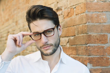 Portrait of a man wearing glasses at brick wall - ALBF00572