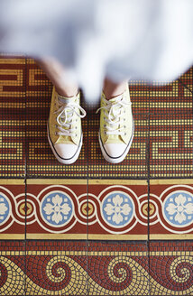Frau in gelben Turnschuhen steht auf Mosaikboden, Teilansicht - ABIF00639
