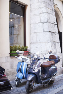 Zwei alte Motorroller parken vor einem Haus - ABIF00640