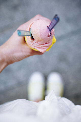 Woman's hand holding ice cream cone with two scoops and spoons stock photo