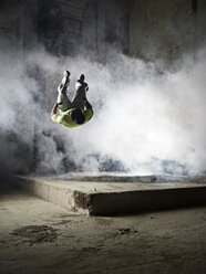 Mann springt bei einer Freerunning-Übung in eine Staubwolke - CVF00851