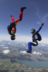 Team of two female skydivers in sit fly and head down positions over Buttwil, Luzern, Switzerland - CUF33644