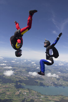 Team von zwei Fallschirmspringerinnen in Sitzflug- und Kopfabsprungposition über Buttwil, Luzern, Schweiz - CUF33644