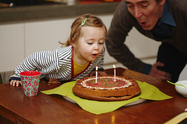Junges Mädchen bläst Geburtstagskerzen auf Kuchen aus - CUF33649