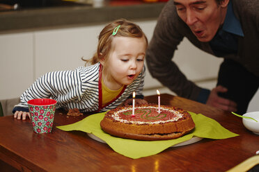 Young girl blowing out birthday candles on cake - CUF33649