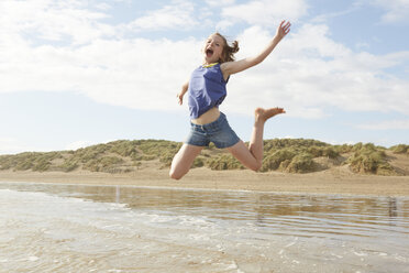 Girl jumping mid air on beach, Camber Sands, Kent, UK - CUF33715