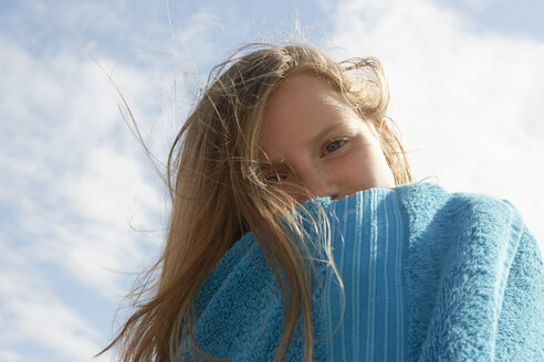 Porträt eines Mädchens, eingewickelt in ein Handtuch an einer windigen Küste - CUF33716