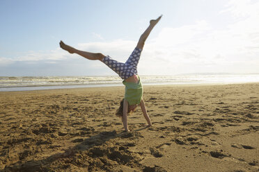Girl doing handstand on beach, Camber Sands, Kent, UK - CUF33722