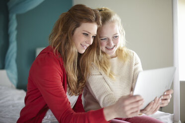 Two teenage girls looking at digital tablet in bedroom - CUF33774