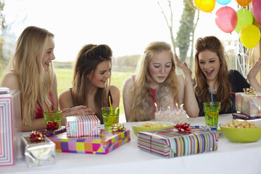 Teenage girl blowing out birthday candles with friends - CUF33782