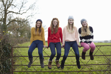 Four teenage girls sitting on gate - CUF33793