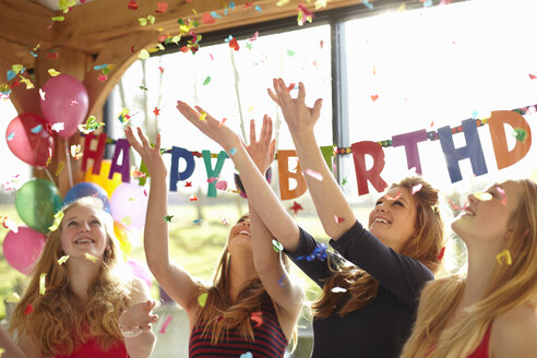 Four teenage girls celebrating with confetti at birthday party - CUF33807
