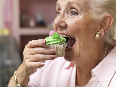 Ältere Frau genießt Muffin im Café, lizenzfreies Stockfoto