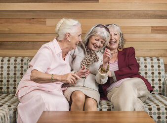 Senior women friends laughing on sofa - CUF33819