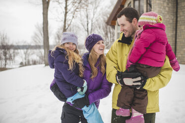 Mutter und Vater tragen ihre Töchter in den Schnee - CUF33901