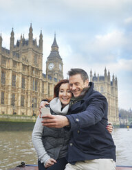 Mature tourist couple photographing selves and Houses of Parliament, London, UK - CUF33936